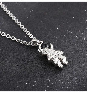 Close-up of silver astronaut pendant with black inlay on glittering dark background