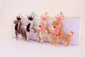 Detail of four crystal-encrusted poodle keychains with crowns in various metallic finishes