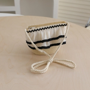 Detail of a mini straw crossbody bag with white chiffon pleats and black decorative ribbons