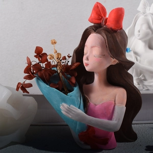 Detail of girl figurine planter with red bow and pink dress holding dried flowers