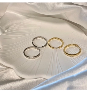 Silver and gold s925 sterling silver hoop earrings on a white shell ceramic tray