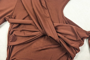 Detail of a brown ruched dress showing the intricate cross-knot design and knit texture