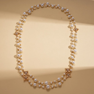 Détail d'un collier de perles multicouche avec flocons dorés et accents de cristal