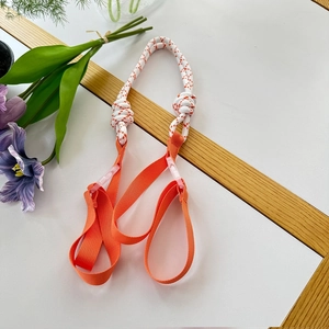 Detail of the orange and white braided shoulder strap with adjustable plastic buckle