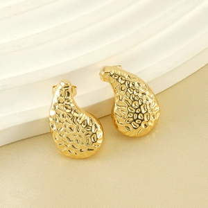 Elegant gold hammered teardrop earrings with irregular texture on a marble base