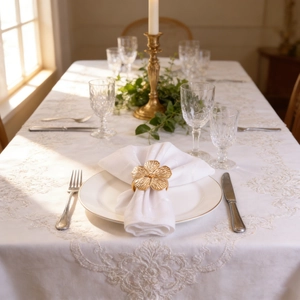 Elegant gold flower napkin ring on white linen set in a luxury wedding table arrangement