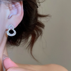 Macro view of silver hollow gourd earrings with micro-paved zircons on model ear