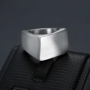 Macro shot of geometric brushed steel ring with matte silver finish on black display