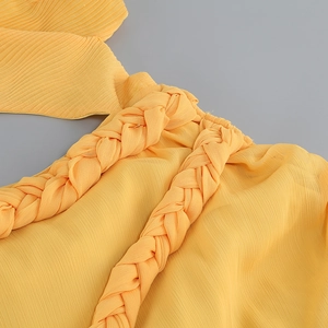 Détail de la robe jaune présentant des bretelles tressées épaisses et du tissu mousseline