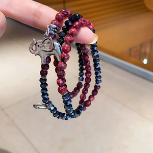 Close-up of bohemian multi-layer beaded bracelet featuring silver elephant charm and red stones