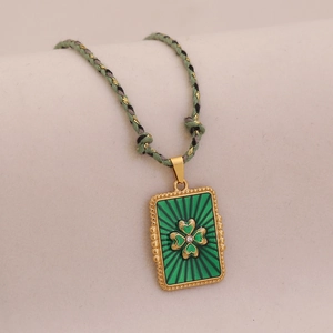 Gros plan d'un pendentif trèfle en émail vert sur un collier en corde tressée