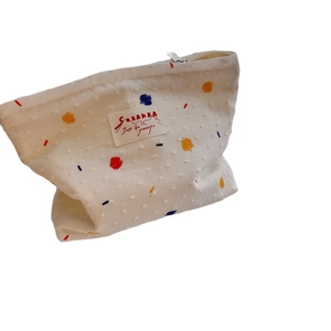 White canvas makeup bag with colorful embroidered dots and secure metal zipper closure