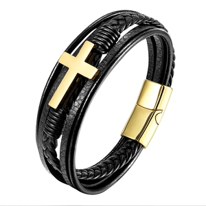 Macro shot of multi-layer black braided leather bracelet with golden cross and magnetic clasp