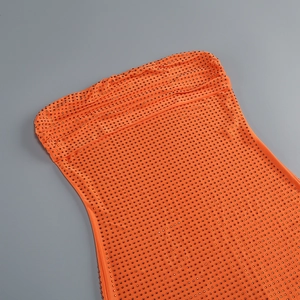Détail rapproché d'une robe moulante orange vif ornée de strass brillants et de fronces