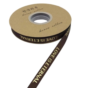 Macro view of brown satin ribbon with LOVE IS ETERNAL gold foil print on a paper spool