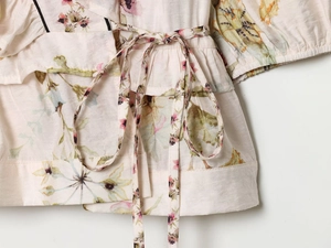 Detail of waist tie and tiered ruffle hem on this floral linen blend peplum blouse