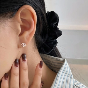 Close-up of heart-shaped 925 sterling silver twist knot stud earring worn on model ear