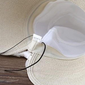 Detailed macro view of the internal mesh lining and elastic strap on the straw sun hat