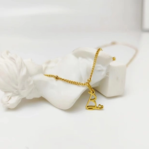 Collana placcata in oro con ciondolo lettera B e dettaglio cuore su statua bianca
