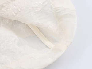 Vue macro détaillée de la texture du blazer en dentelle blanche et de la finition du bord