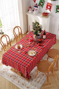 Close-up of red and green plaid festive Christmas tablecloth on a wooden dining table