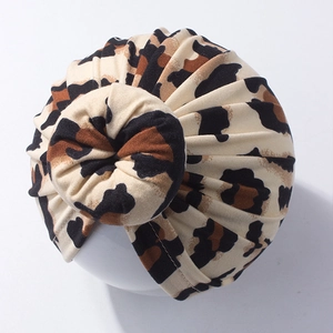 Close-up of leopard print baby turban hat with top knot detail on a white mannequin