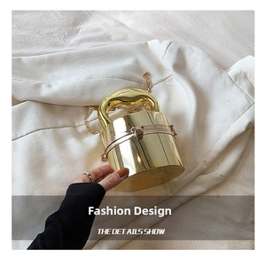 Detail show of cylindrical gold acrylic evening bag with ball clasp and metal chain