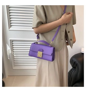 Detail view of purple leather crossbody bag with metal twist lock worn by a model