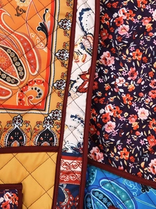 Detail of multi-color quilted fabric with paisley, floral patterns and stitching