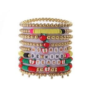 Close-up of Teacher themed layered beaded bracelets with apple charm on display stand