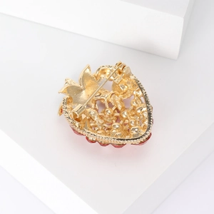 Fresh strawberry brooch with red enamel and golden finish on a white geometric block