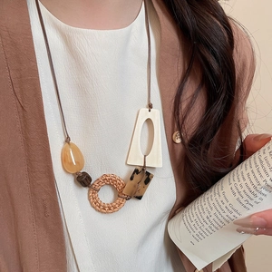 Detail of bohemian necklace with woven rattan ring and geometric beads on a female model