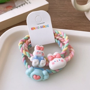 Détail de breloques lapin et cœur en résine sur des chouchous tressés pastels