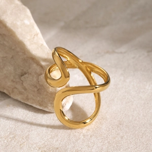 Detailed side view of a gold-plated irregular layered ring on a textured stone surface