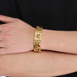Close-up of men's gold chunky skull chain bracelet with red crystal eyes on a wrist