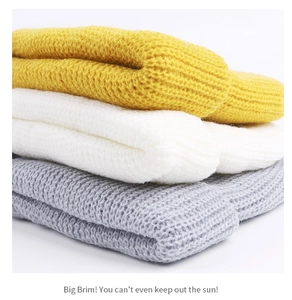 Detail of yellow, white, and grey chunky knit beanies showing soft fabric textures