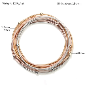 Set of nine spring coil bracelets in gold, silver, and rose gold with metal beads