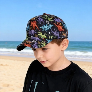Jeune garçon portant une casquette de baseball colorée à imprimé dinosaure à la plage