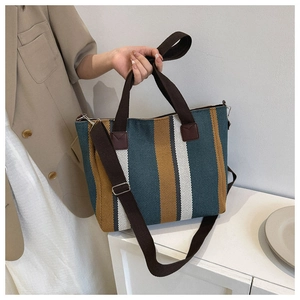 Detailed shot of a striped canvas tote bag with brown straps and detachable shoulder strap