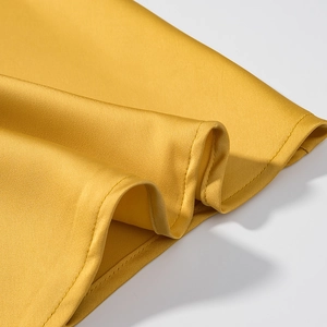 Gros plan détaillé du tissu en satin jaune montrant les coutures et la texture soyeuse