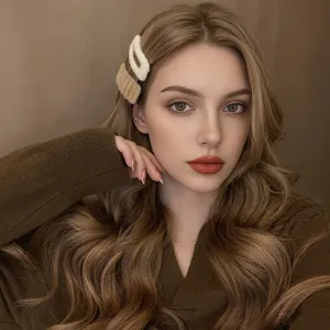 Detailed close-up of a plush cream hair clip worn on a model hair for autumn style
