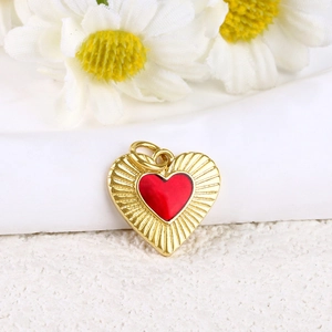 Macro view of 18k gold heart pendant with red enamel and radial sunburst texture