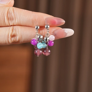 Macro shot of colorful cat eye stone tassel earrings held to show texture and size