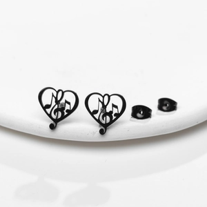Detail of black heart musical note earrings with treble clef design on white stand