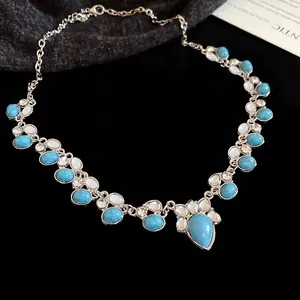 Ethnic silver necklace with turquoise teardrop pendant and opal stones on black velvet