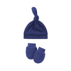 Flat lay of newborn dark blue knotted hat and matching scratch mittens on white background