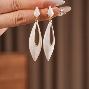 Detail showing white marble teardrop earrings with elegant golden metal borders