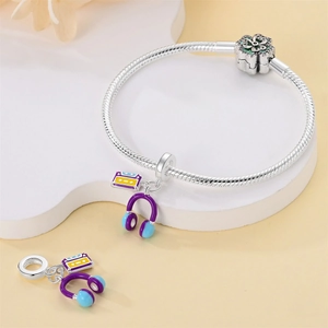 Close-up of snake chain bracelet with purple headphone and yellow cassette tape charms