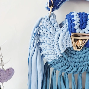 Macro shot of hand-woven blue gradient fabric bag with triangular metal clasp and fringe