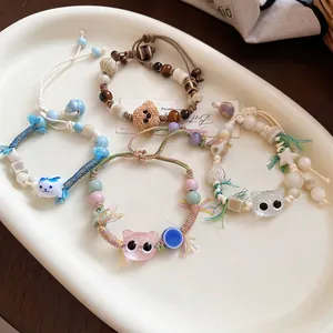 Handmade woven bracelets with cute ceramic cat and bear charms on white tray